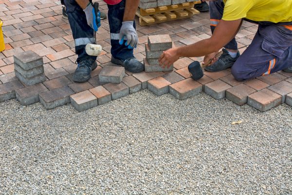 male construction workers collaborating together to construct a brick wall