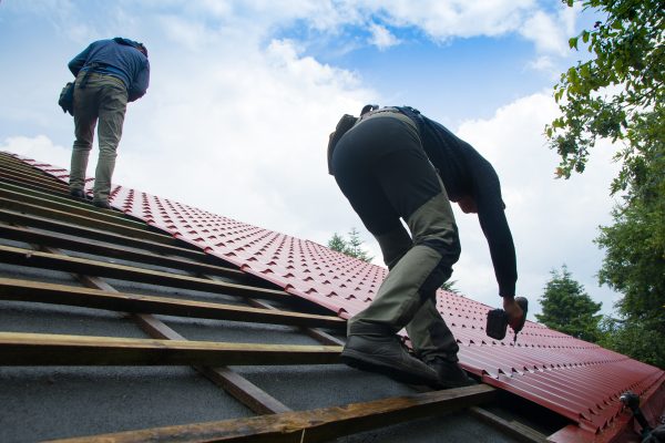 Roofers working on roof structure of building on construction site,Roofer using air or pneumatic nail gun and installing Metal Sheet on top new roof.